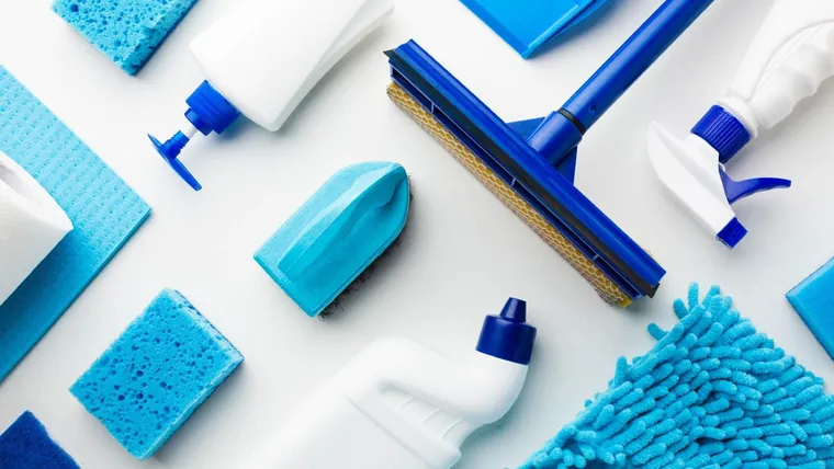 Materiais de limpeza organizados sobre superfície clara — rodo, esponjas, panos de microfibra e frascos (foto de banco de imagens do acervo da Uniclean)